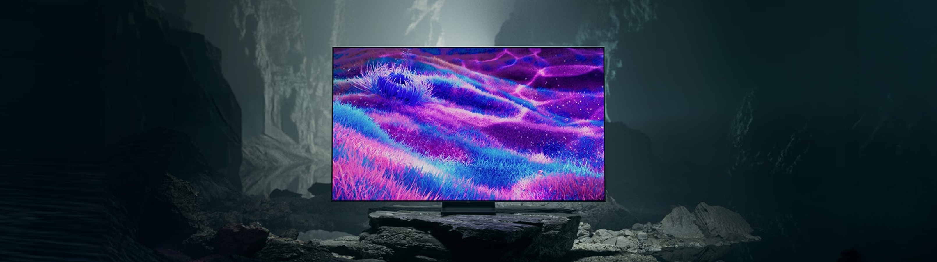 TV screen displaying a vibrant abstract pattern in a dark, rocky setting