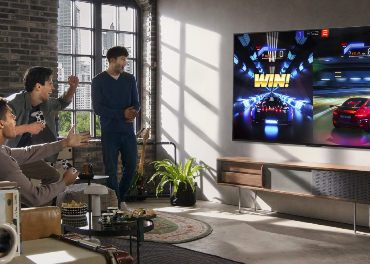 Two men playing video games in a modern living room with a large TV screen displaying a racing game.