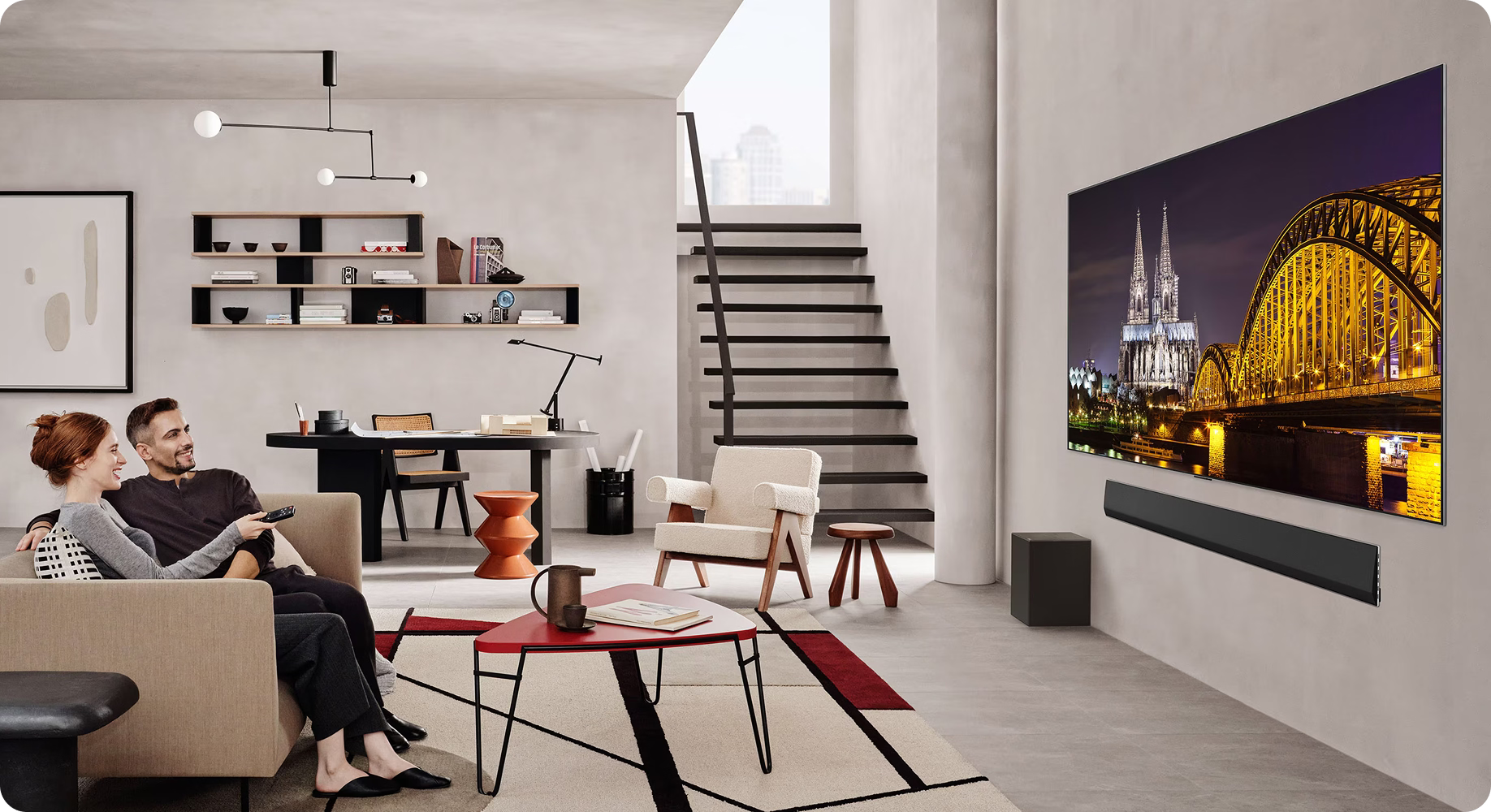 Modern living room with a couple sitting on a sofa, watching TV displaying a cityscape.