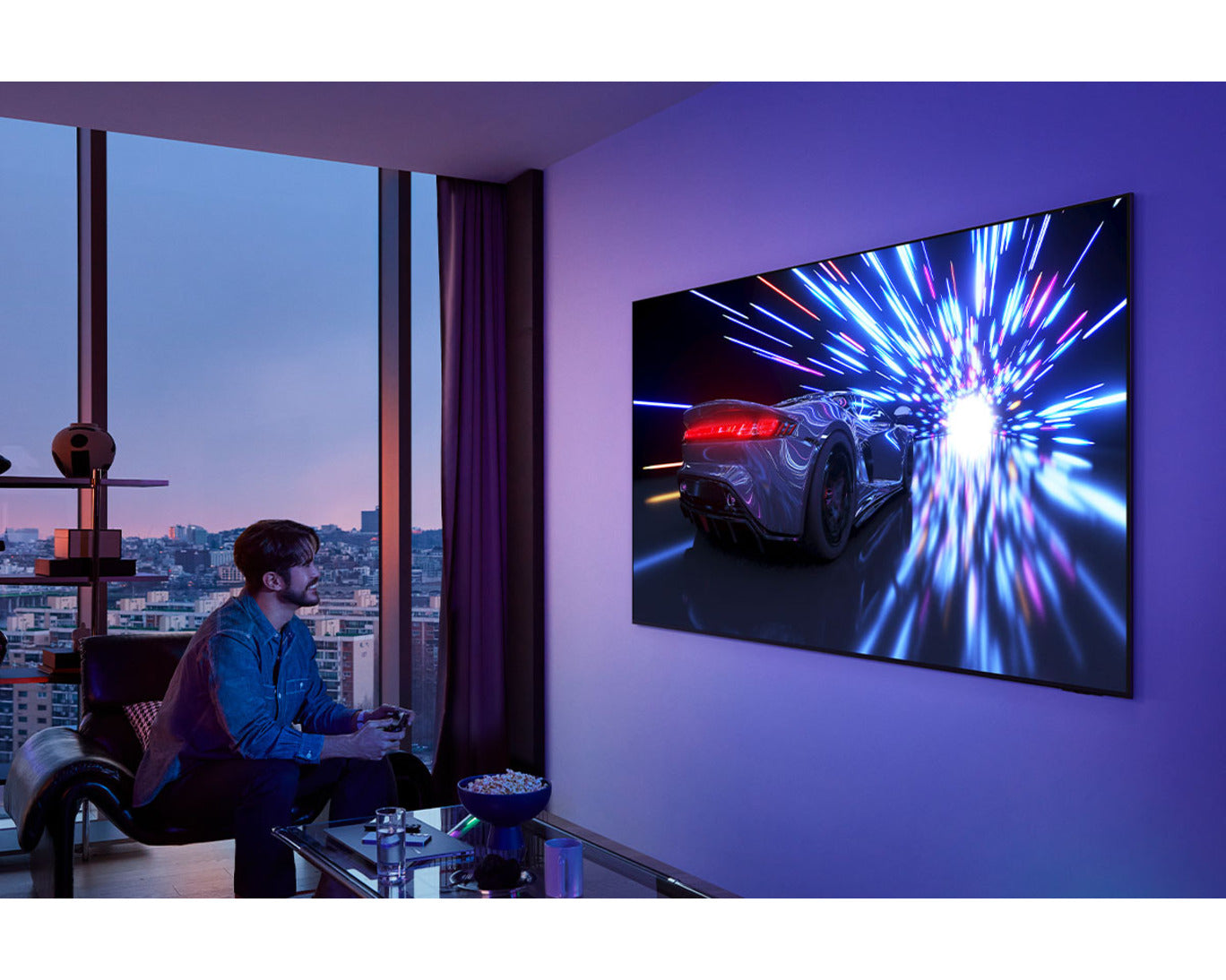 Person watching a car on a large TV screen in a room with cityscape view