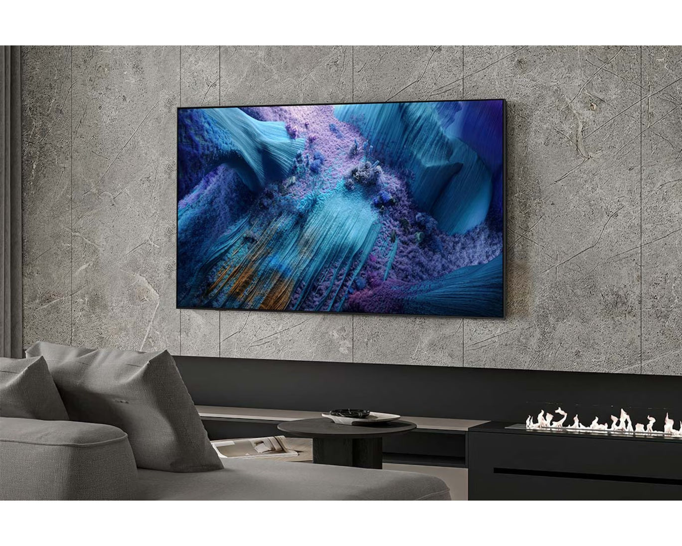 Modern living room with a large TV displaying abstract art, gray sofa, and fireplace.