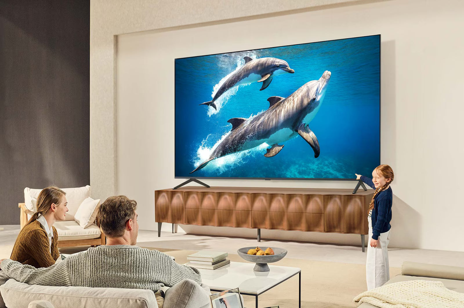 Living room with people watching dolphins on a large TV screen.