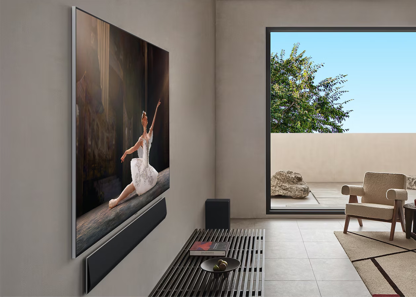 Modern living room with a large TV displaying an image of a dancer, with a chair and table in the foreground.