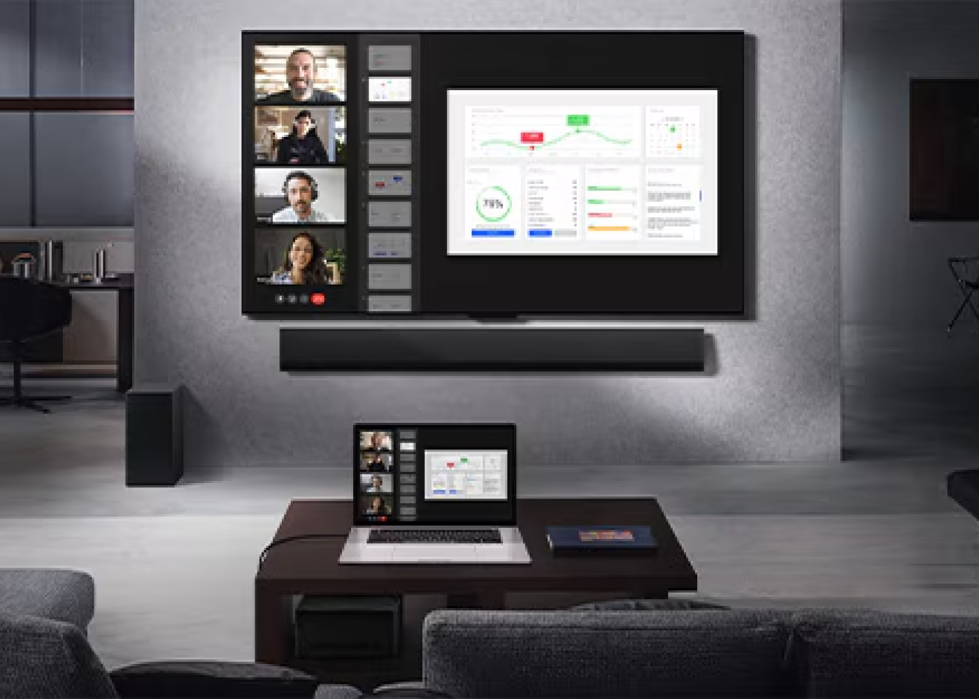 Modern office setup with large screen displaying video call and graphs, laptop on desk.