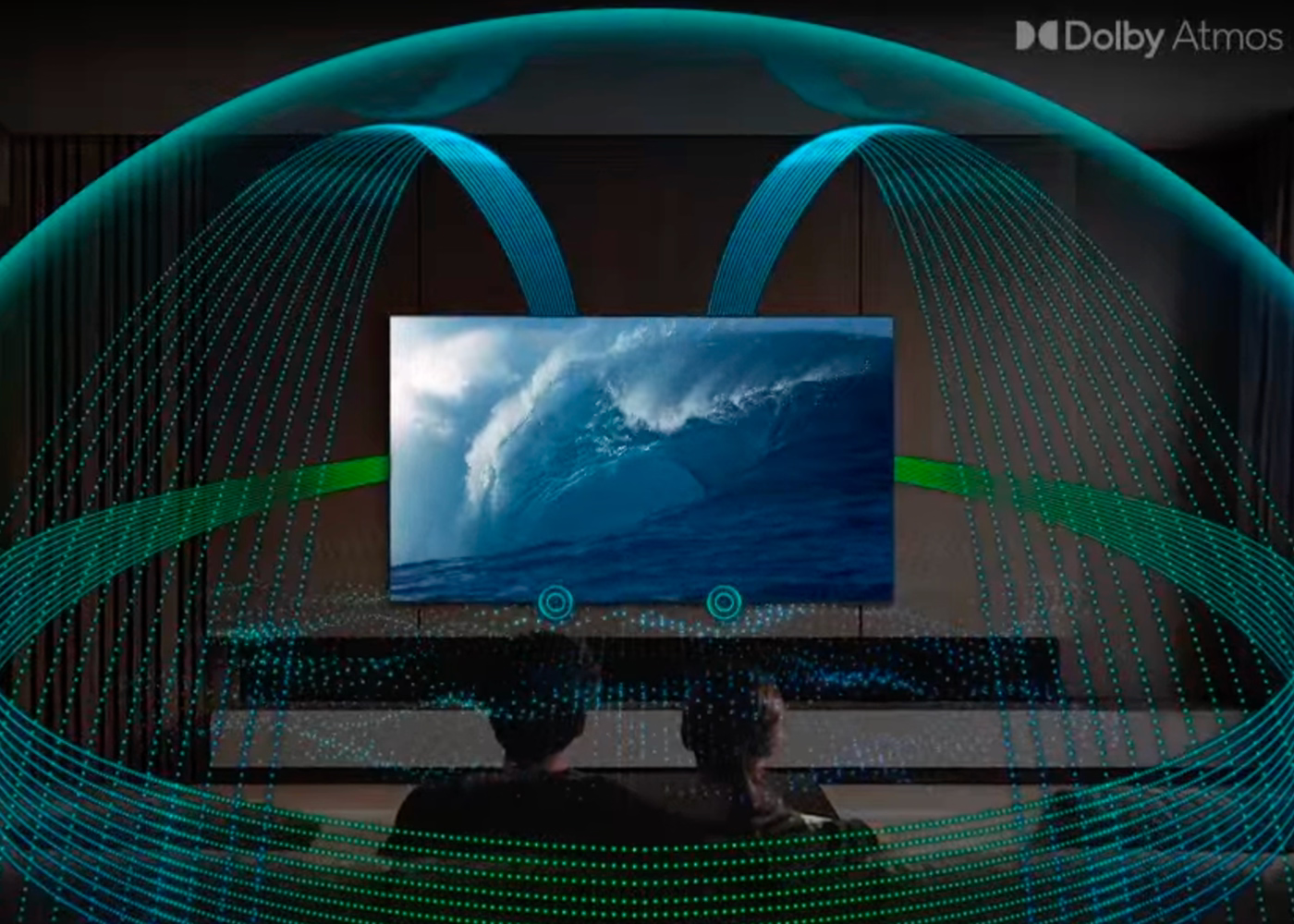 Two people watching a large screen displaying a wave, with Dolby Atmos branding.
