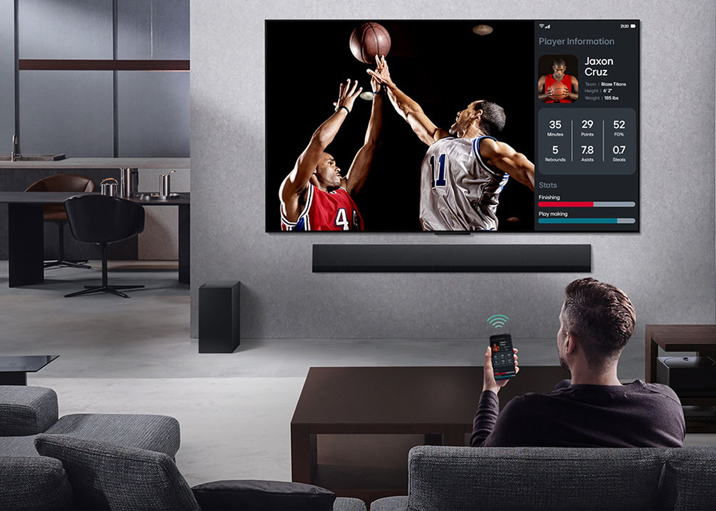 Person watching basketball game on TV with smartphone in living room