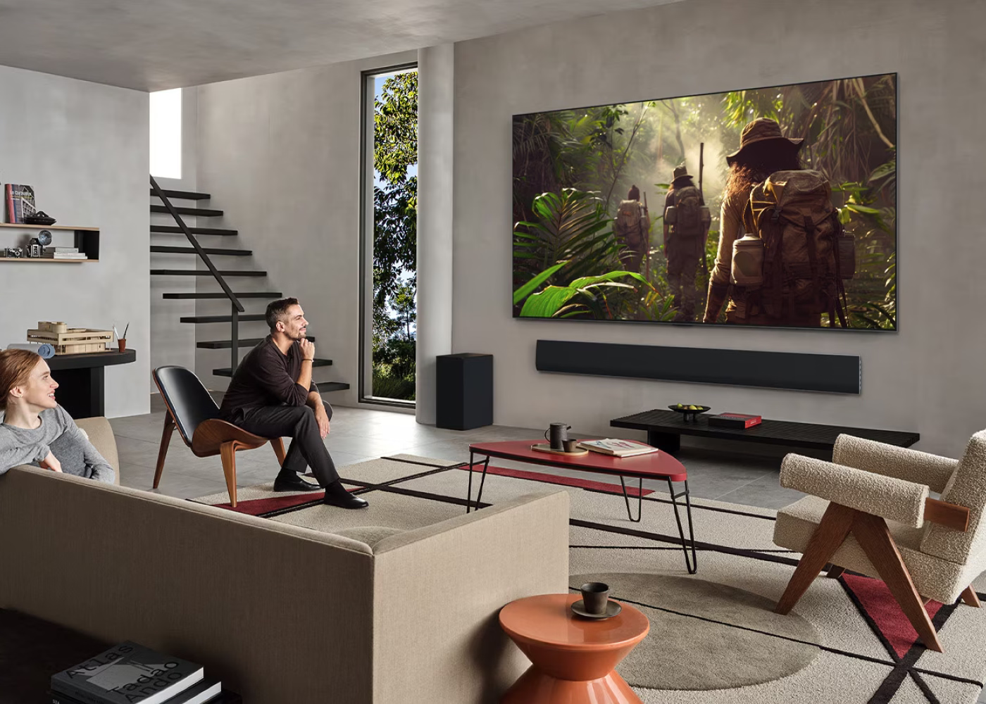 Living room with a large TV displaying a nature scene, people in a forest.